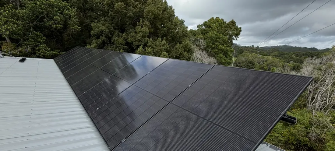 Rows of solar panels on a roof under a blue sky