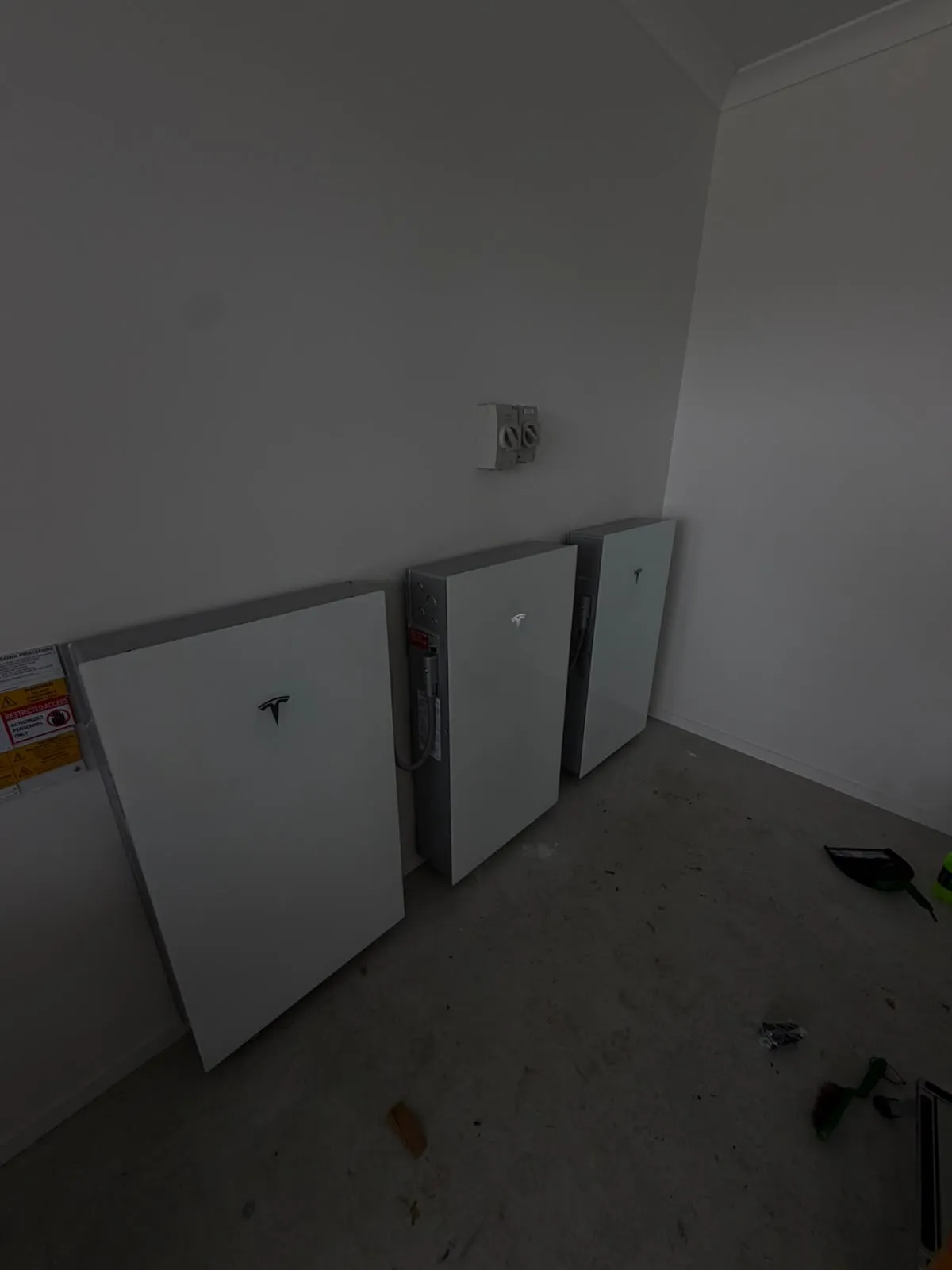 A wall-mounted home battery installed beside a switchboard